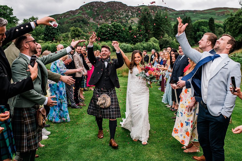 Bride and groom celebrate as they walk back down aisle through confetti thrown by their loved ones